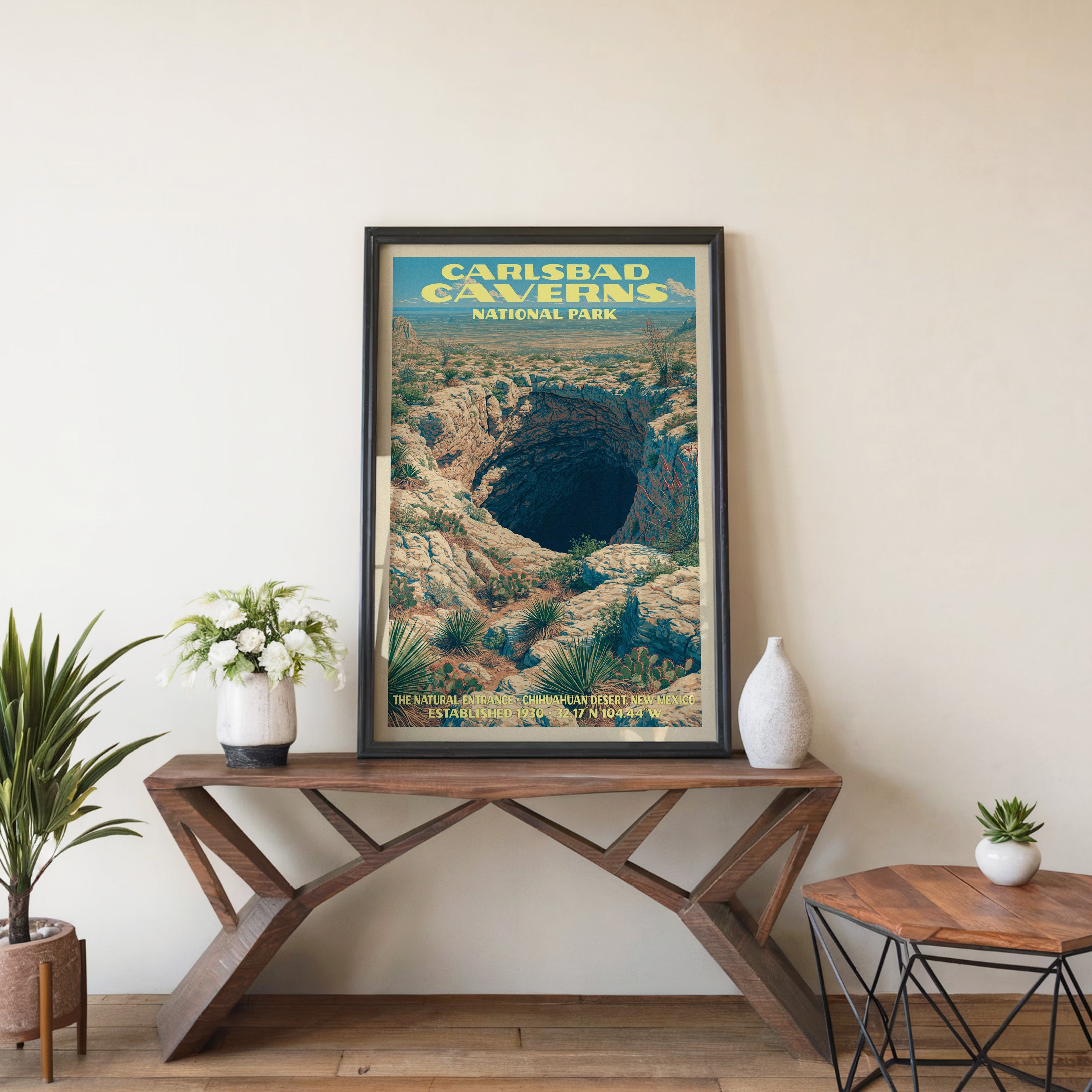 Carlsbad Caverns Natural Entrance wall art in black, leaning on a walnut console with white anemones