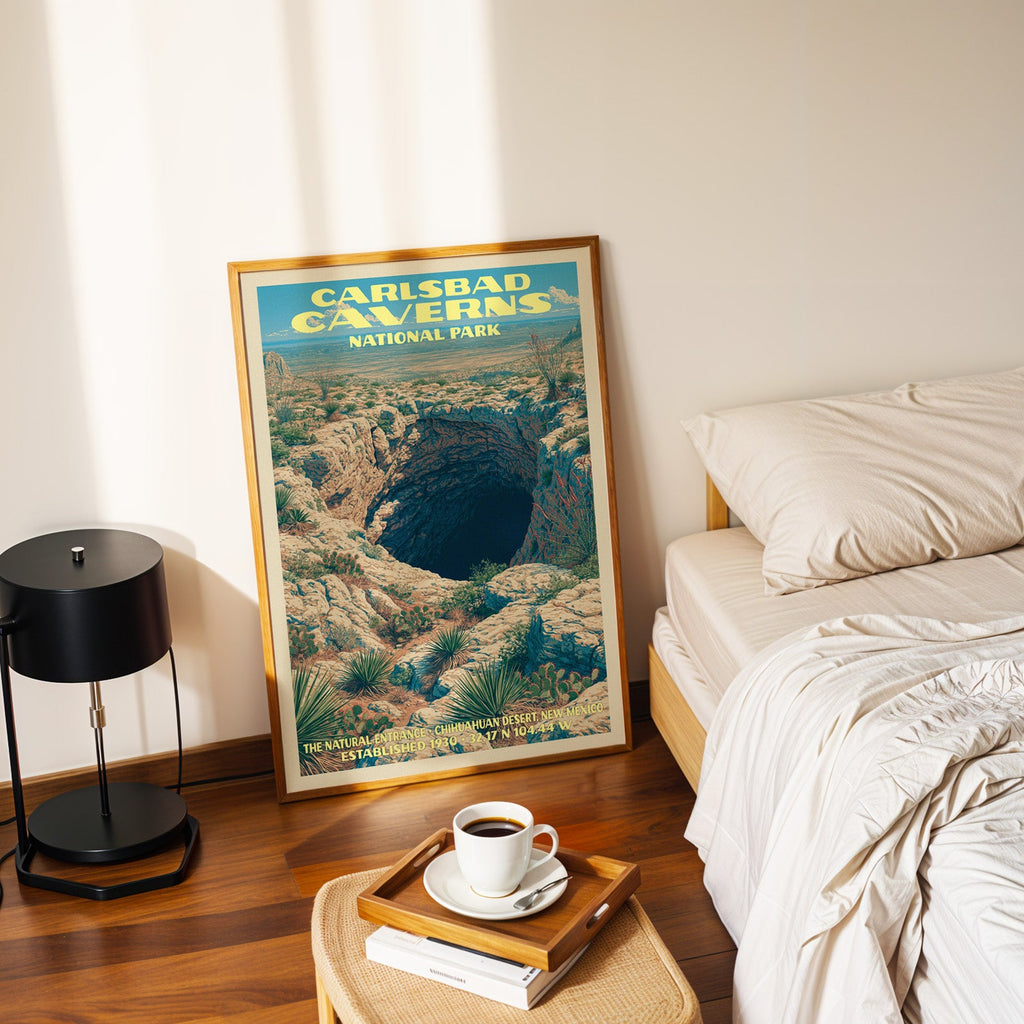 Natural Entrance Carlsbad Caverns poster in a gold frame on the floor beside a made bed and a black lamp