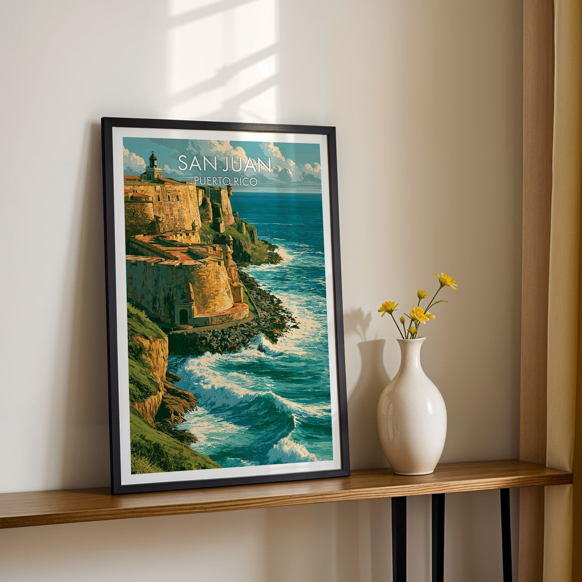 Golden sandstone fort walls in a black frame on a narrow wood shelf with yellow daisies and a sunlit cream wall