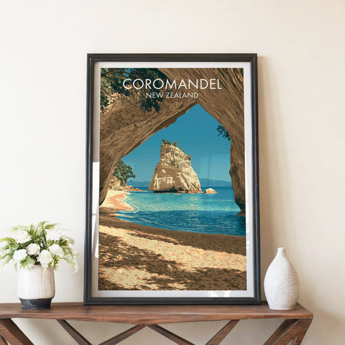 Coromandel sea arch poster in a black frame on a walnut console with white peonies and a stone vase