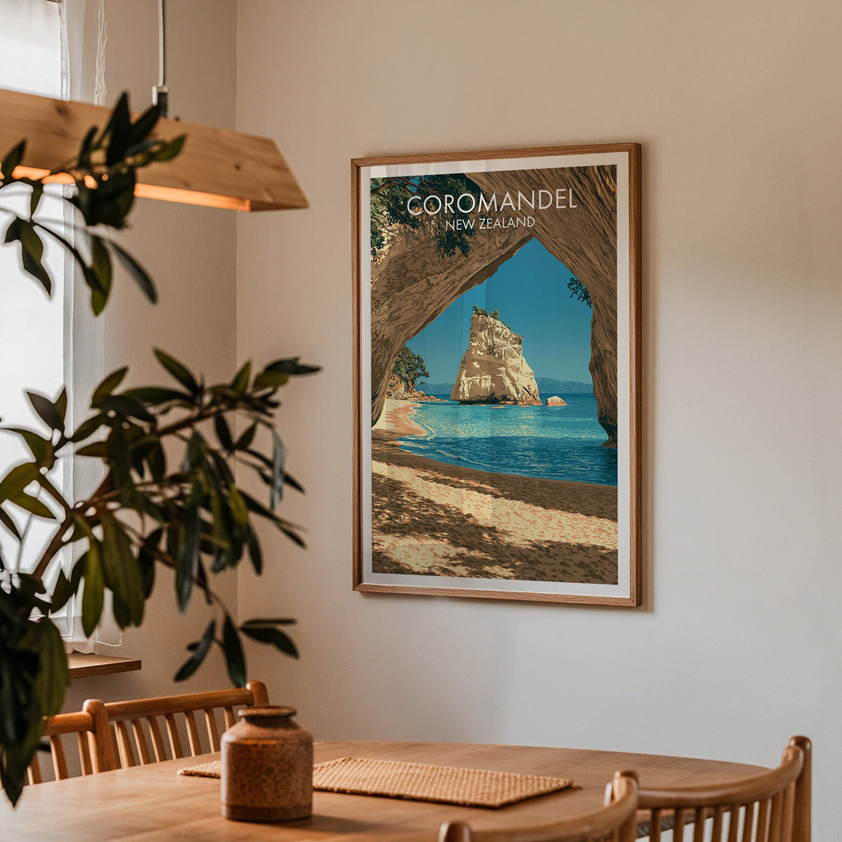 Coromandel beach poster in a dining corner with an oak table, spindle chairs and a wood pendant light