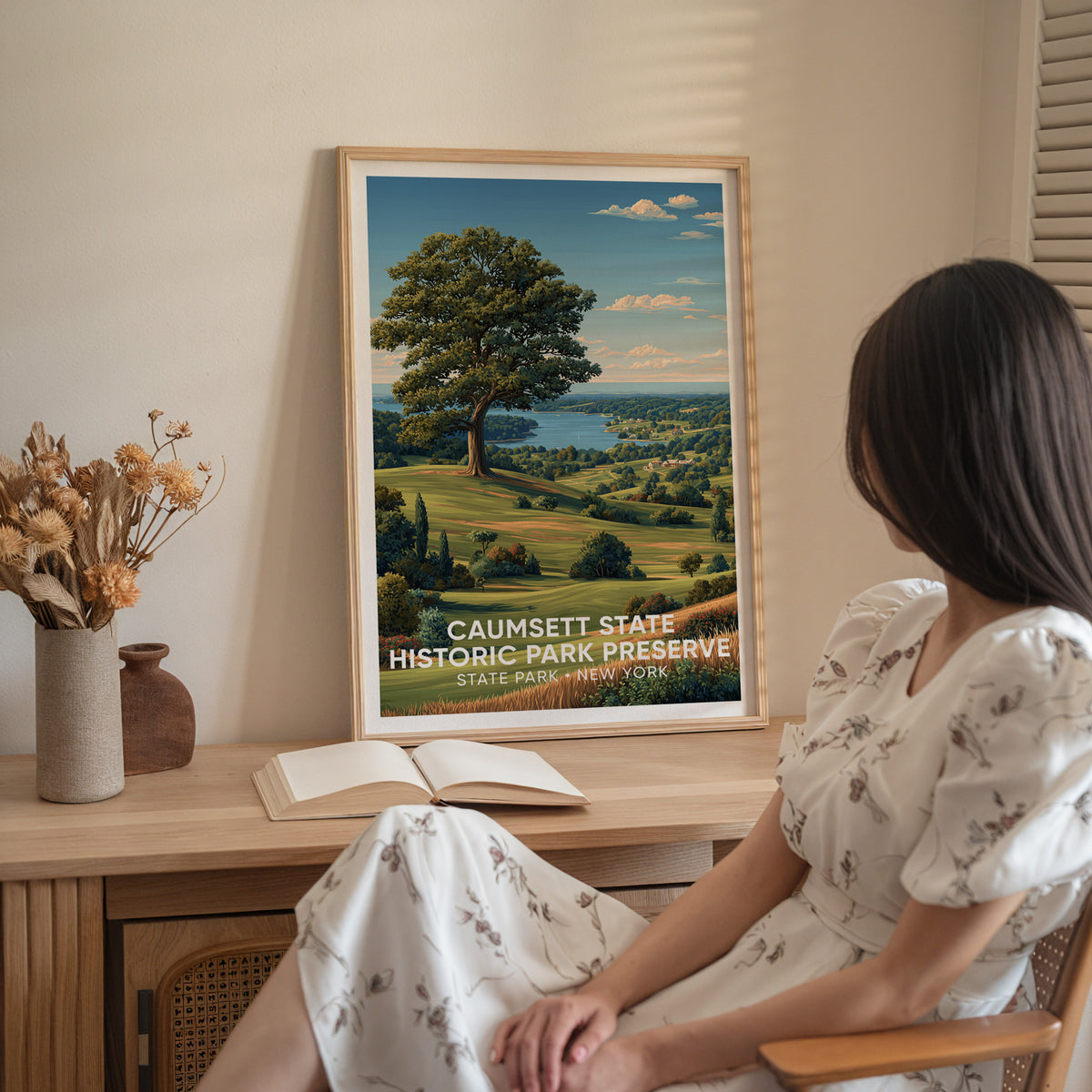 Woman in a white dress sitting by a sideboard that holds the framed Caumsett meadow print