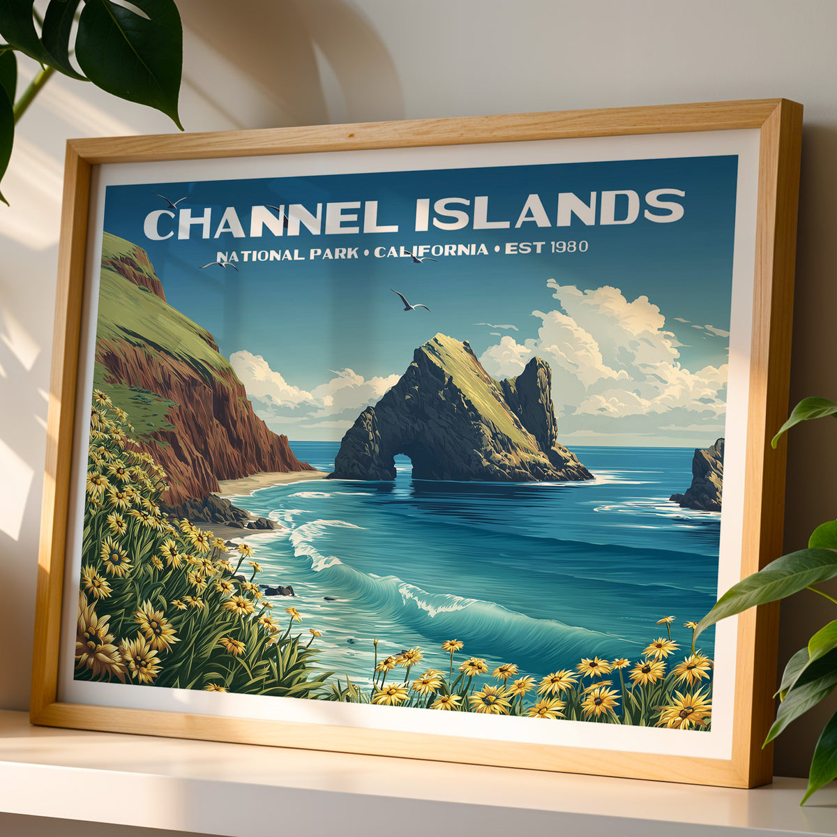 Channel Islands National Park wall art print in a light oak frame, leaning on a white shelf in warm sunlight beside a monstera plant