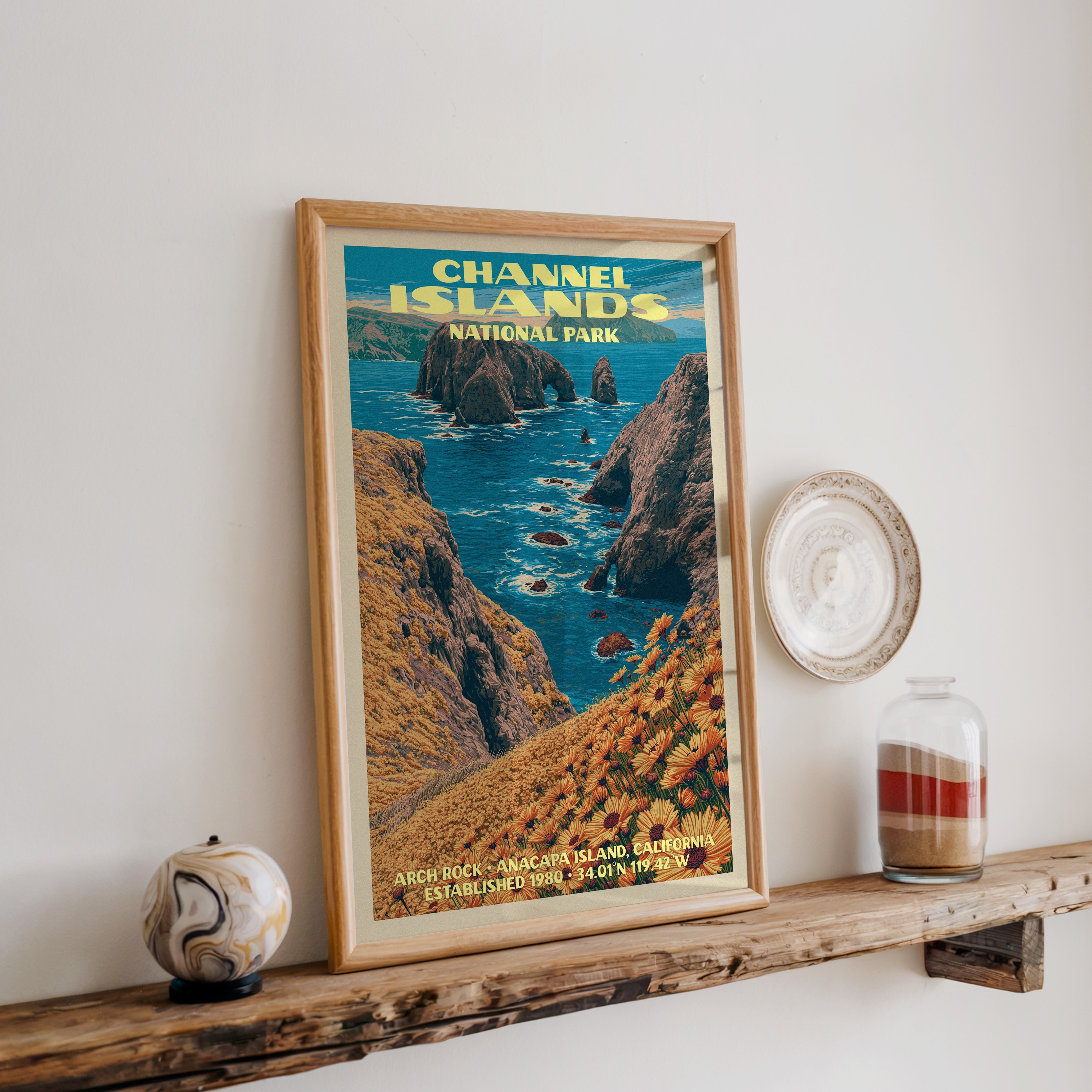 Channel Islands Arch Rock print in oak, leaning on a reclaimed wood ledge with a stone sphere and sand jar