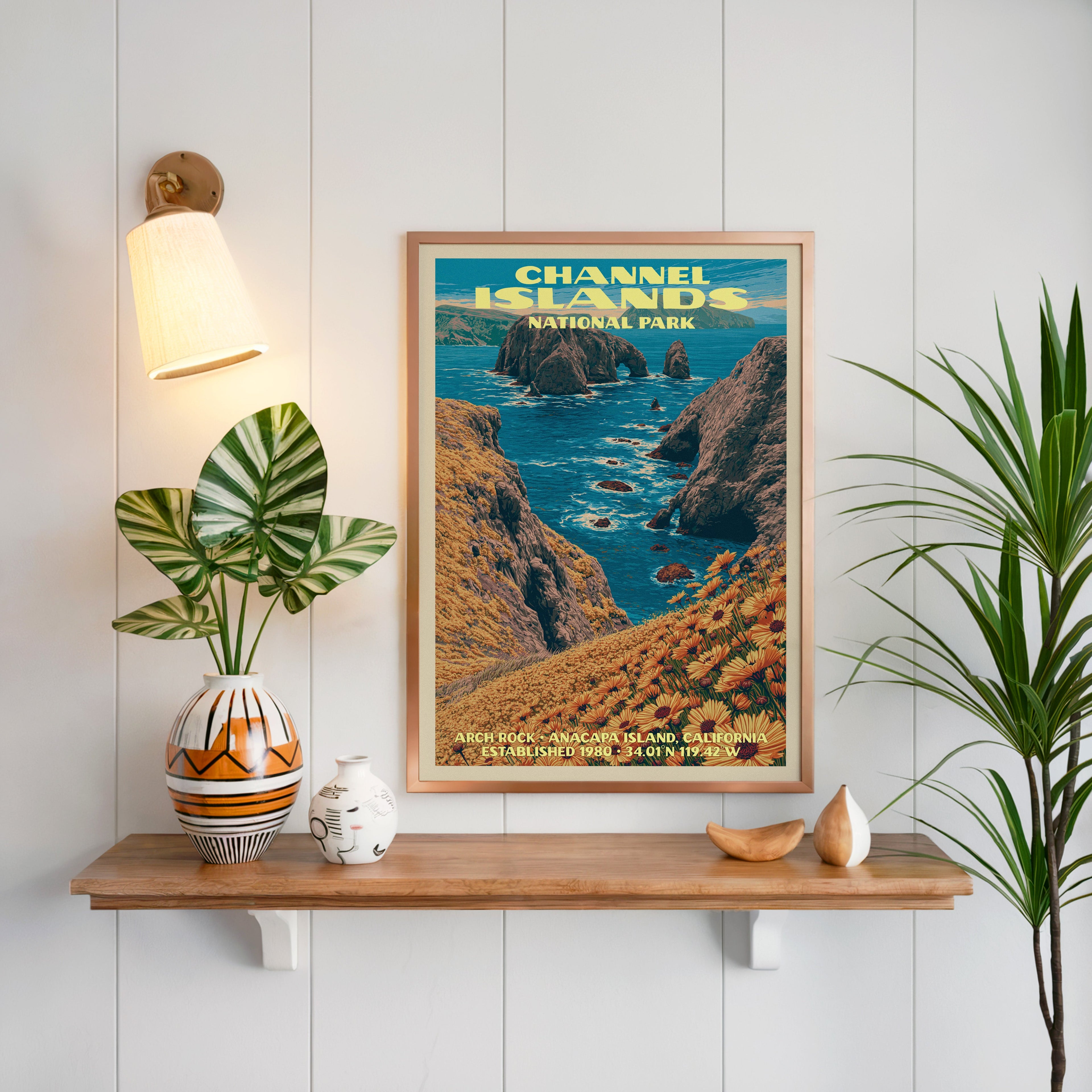 Arch Rock Channel Islands print framed on white panelling above an oak shelf with a patterned vase and sconce
