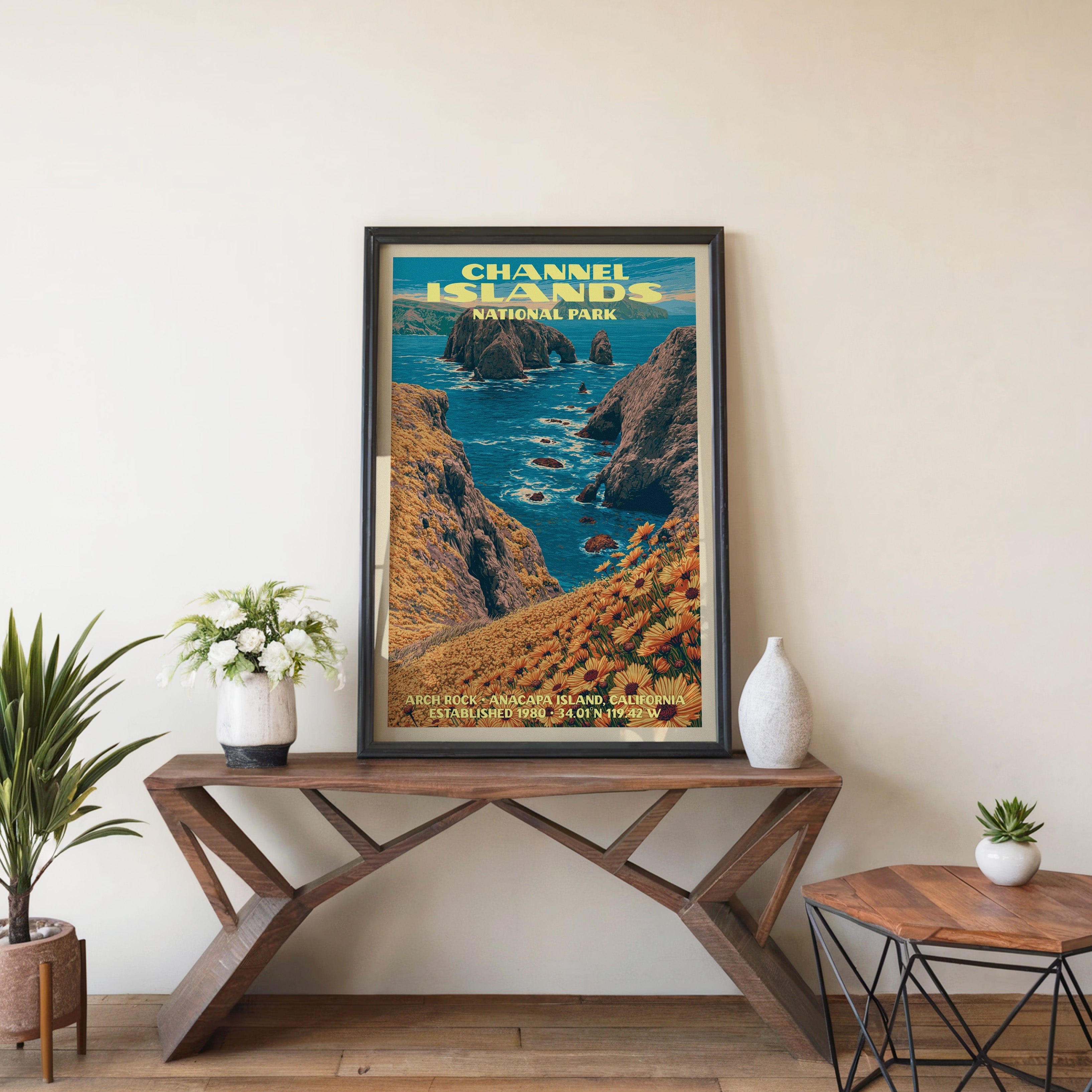 Channel Islands Arch Rock wall art in black, leaning on a walnut console with white anemones and a vase