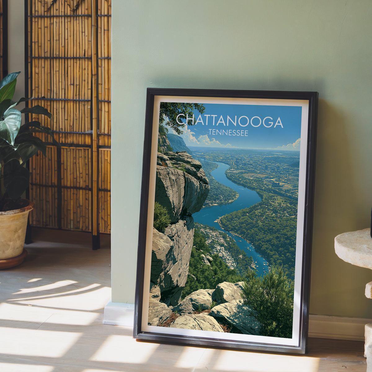 Chattanooga bluff print in a black frame on a sage green wall with a bamboo screen and anthurium