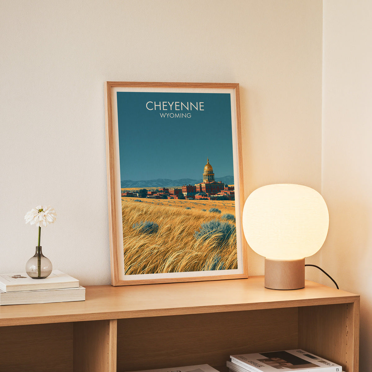 Slim oak framed Cheyenne print standing on a console with a globe lamp and white daisies
