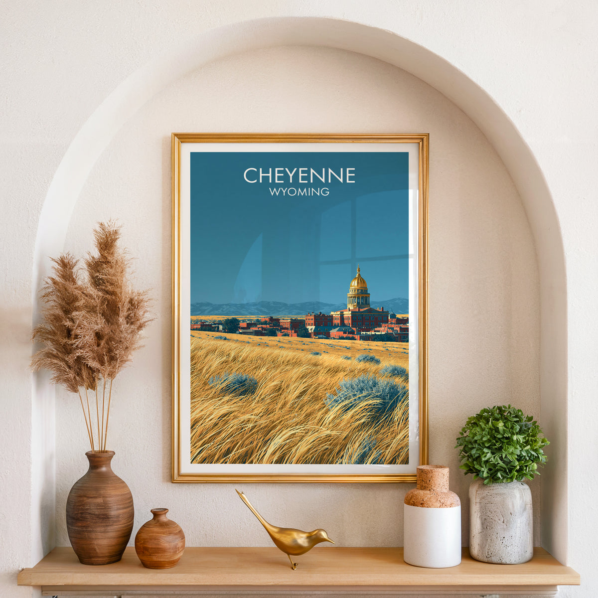Cheyenne travel poster in a gold frame in an arched niche with pampas grass and a brass bird