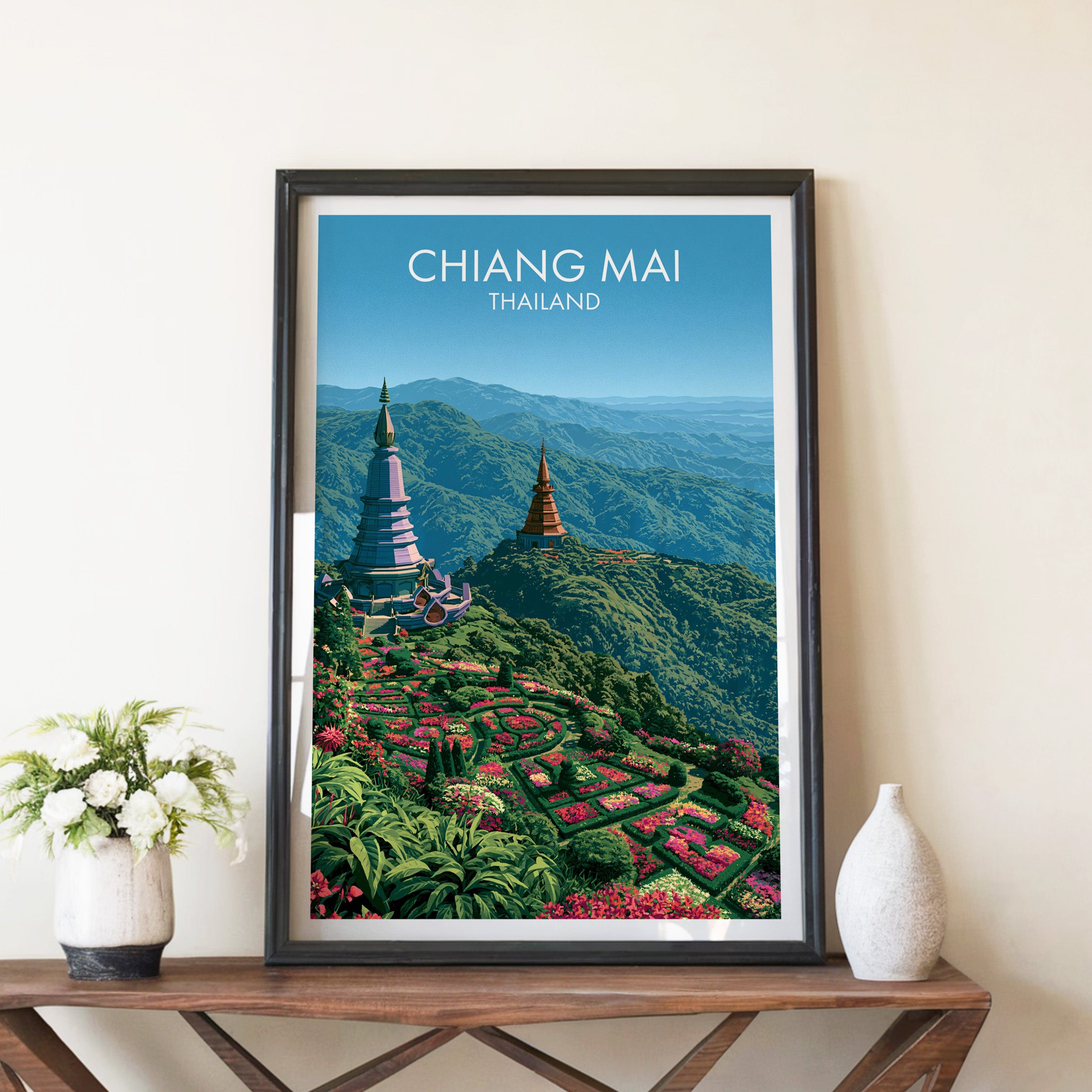 Chiang Mai Thailand travel poster in a black frame on a wooden console table with white flowers