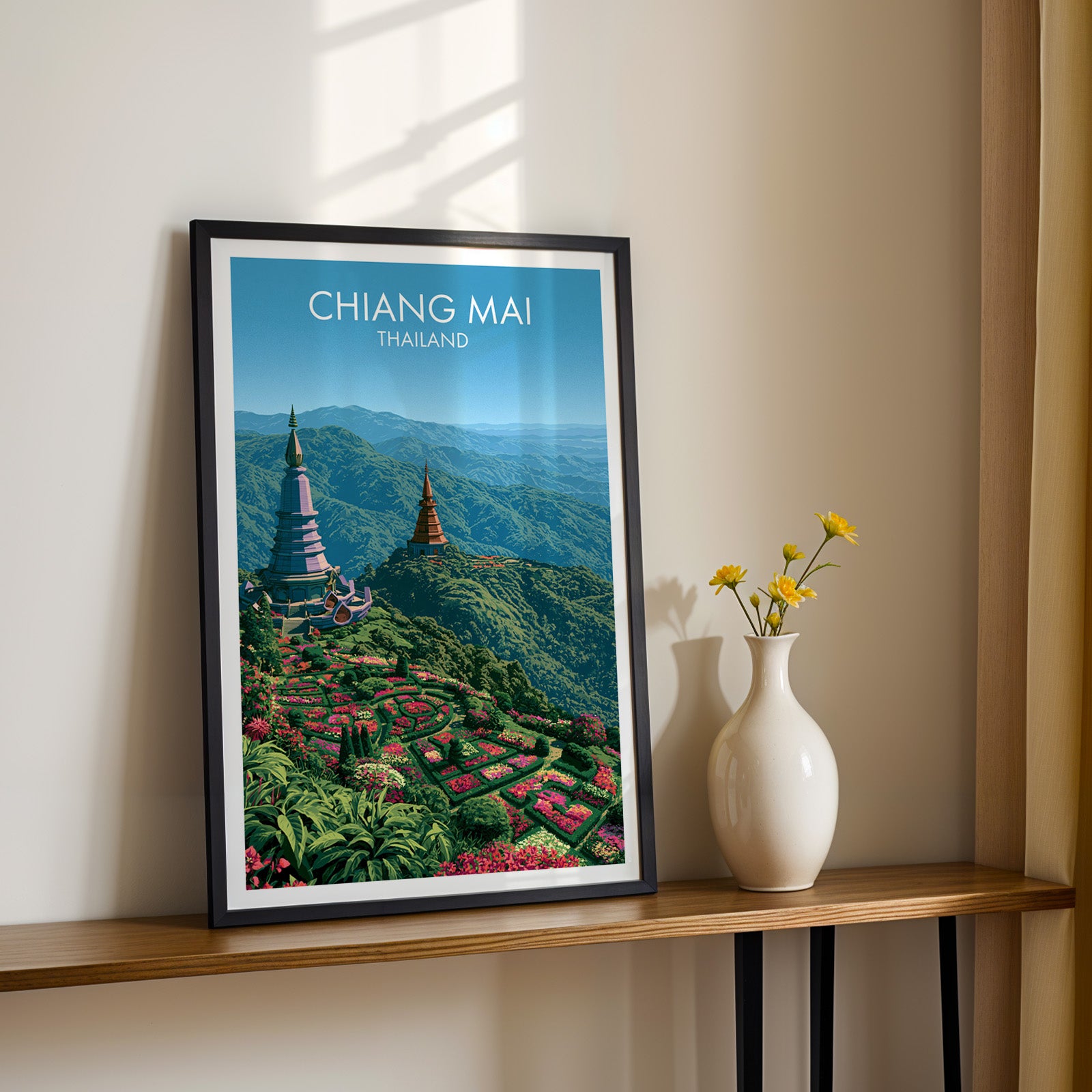 Black framed Chiang Mai Thailand print on a narrow hallway console in sunlight, styled with yellow flowers