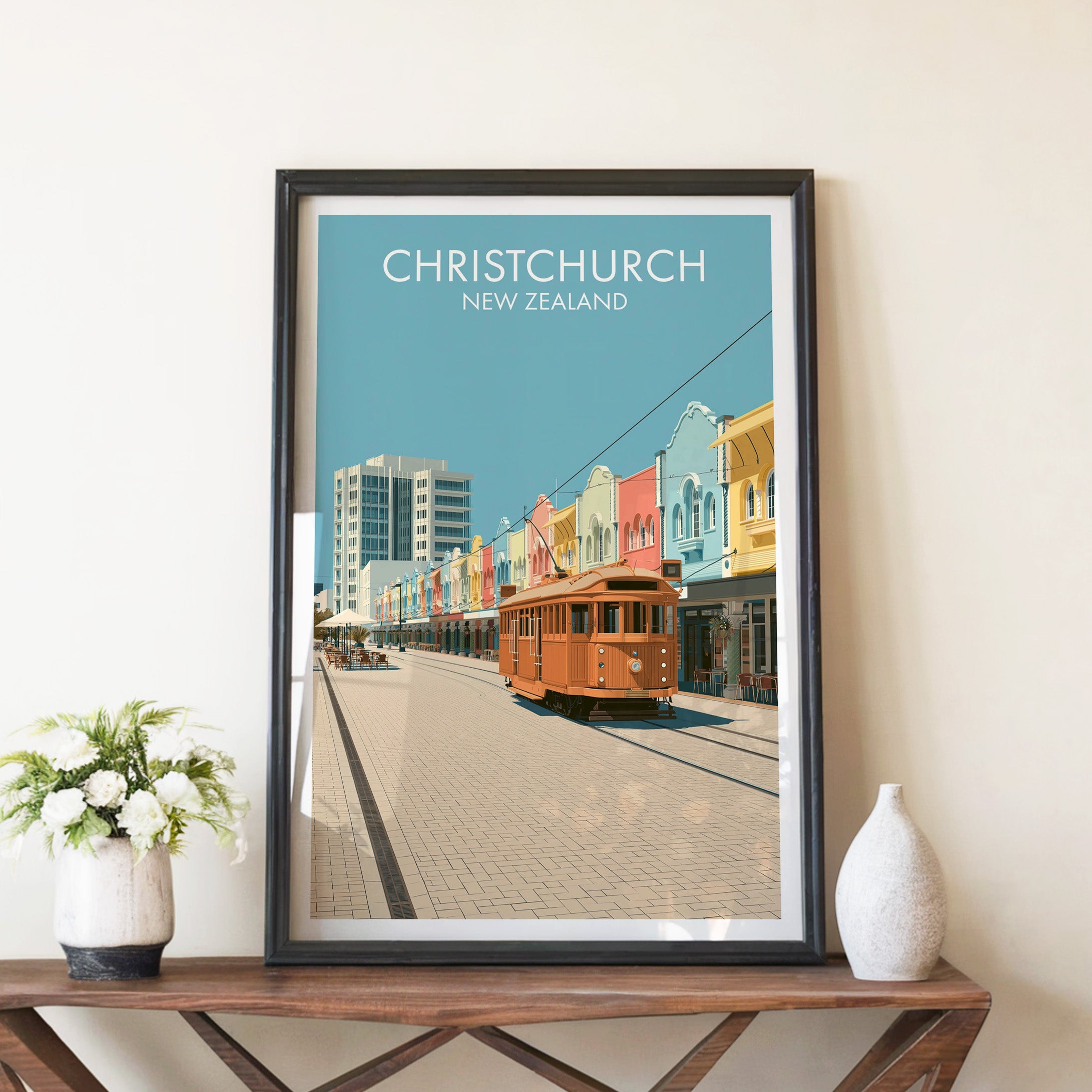 Christchurch poster in a black frame on a walnut console with white peonies and a tall ceramic vase