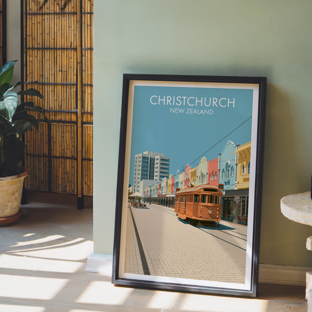 New Zealand tram street artwork in a black frame on a pale wood floor by a sage-green wall and bamboo screen