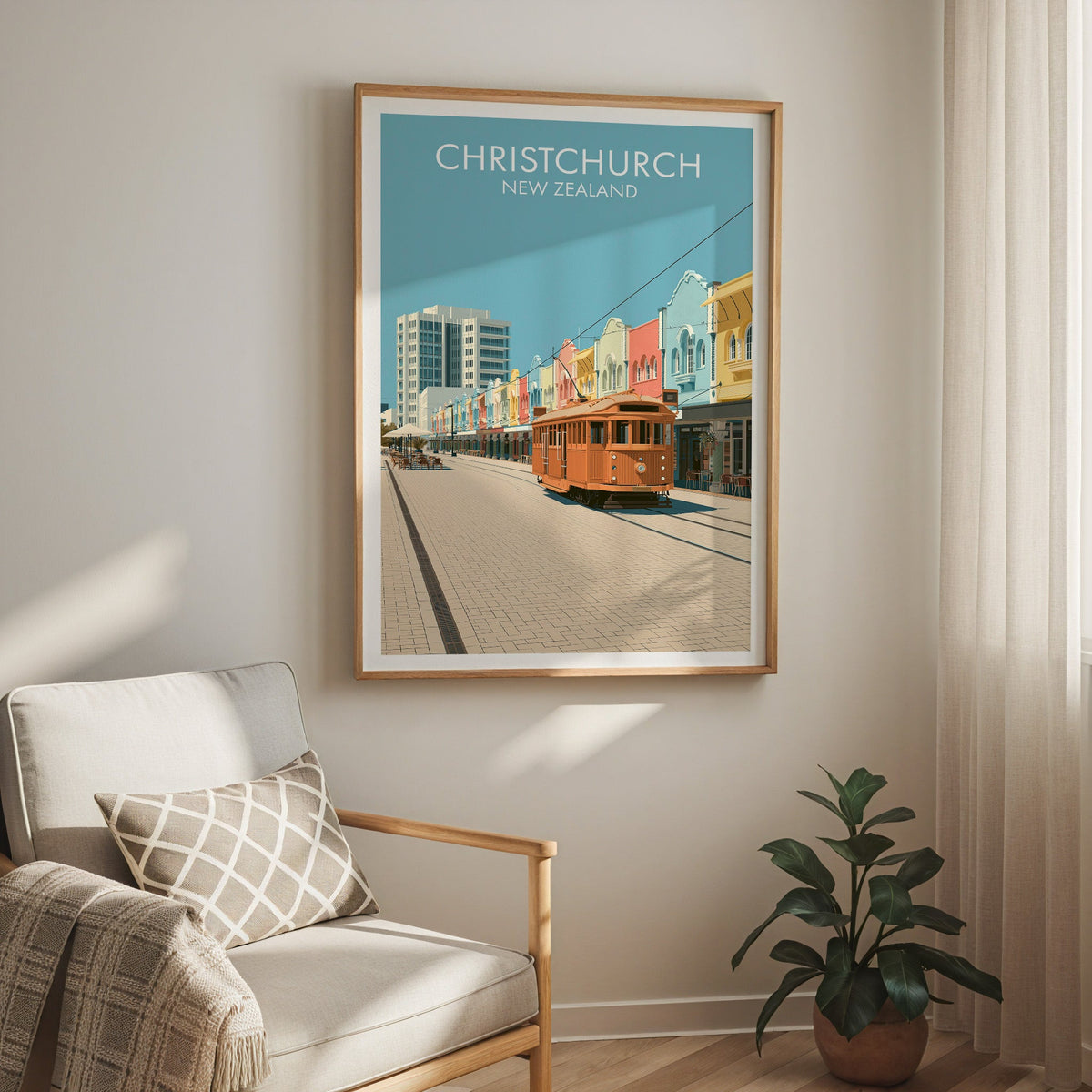 Christchurch print above a cream armchair with a sheer curtain and a rubber plant in a terracotta pot