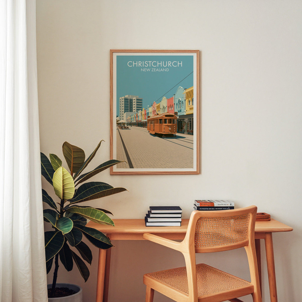 Christchurch travel poster above a wooden home-office desk with a cane chair and a rubber plant