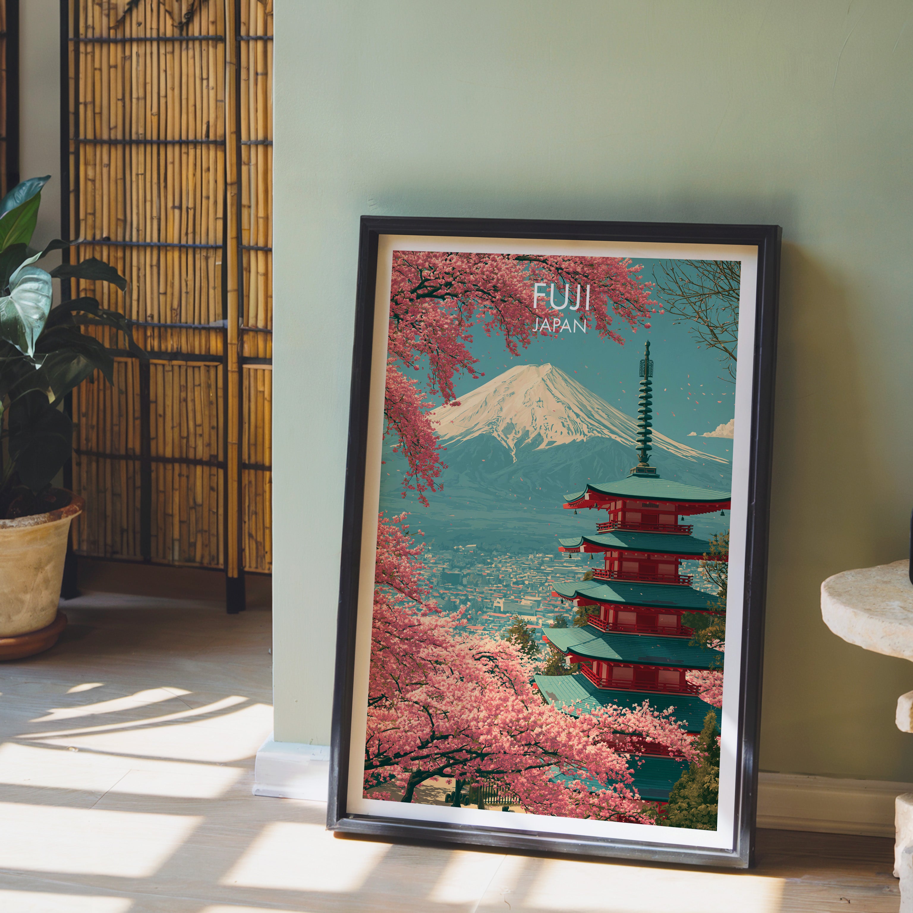 Mount Fuji Japan wall art in a black frame leaning against a sage green wall beside a bamboo screen