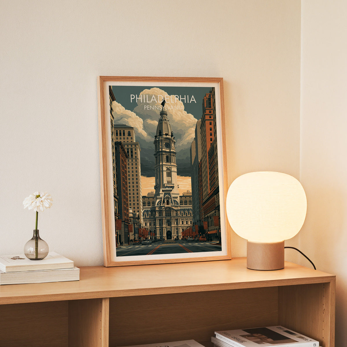 Slim oak framed Philadelphia City Hall poster on a console with daisies in a glass jar and books