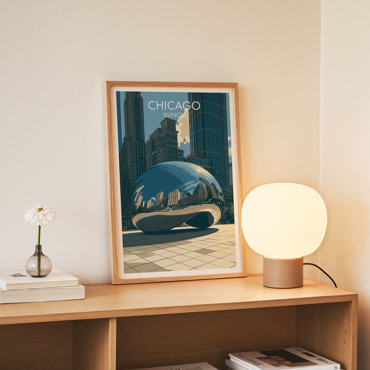 Chicago Bean wall art in a slim oak frame on an oak console beside daisies in a glass jar and books.