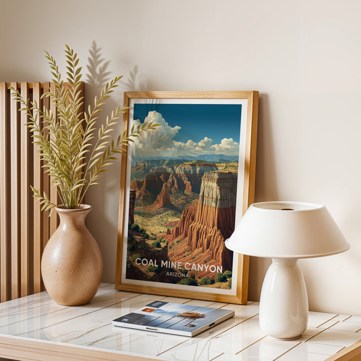 Coal Mine Canyon travel print in oak on a marble table with a dried-leaf vase, lamp and magazines.