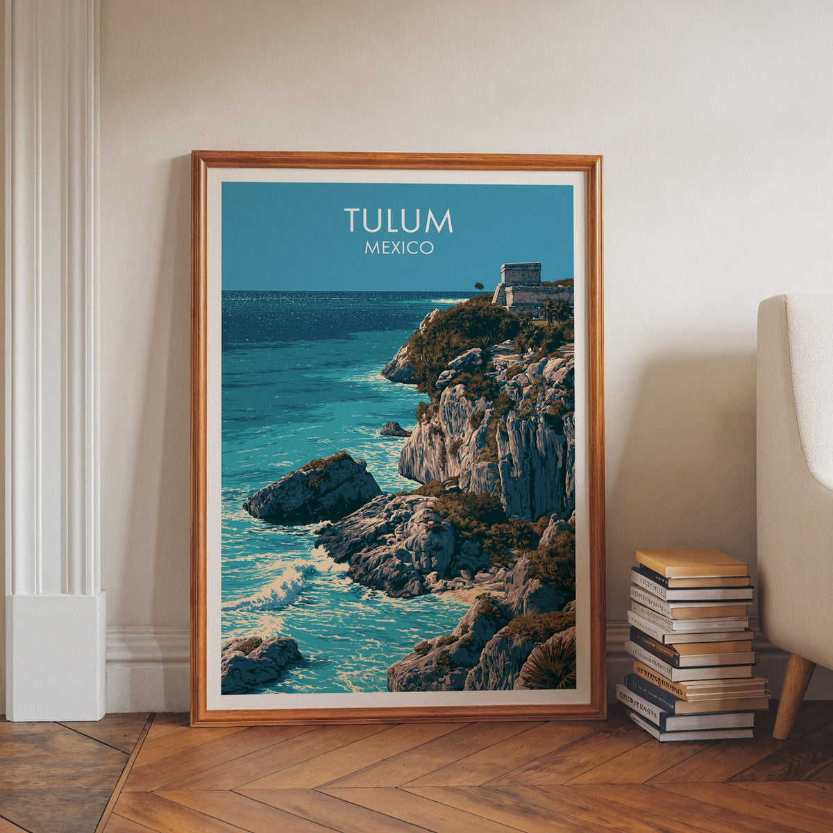Ancient ruin and deep blue water in a walnut frame leaning on a herringbone floor beside books.