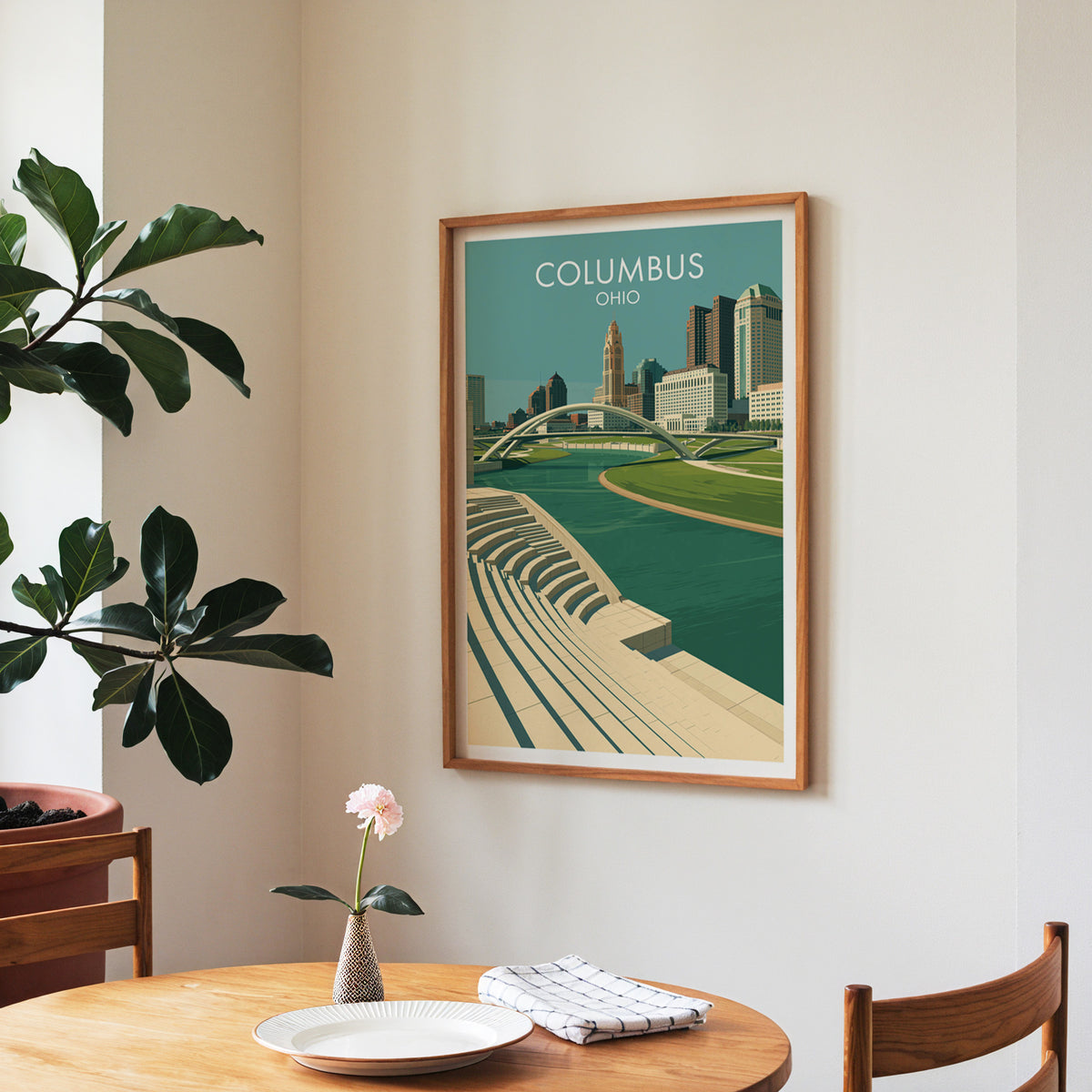 Ohio riverfront print in a walnut frame in a dining corner with a round table, checked runner and roses.