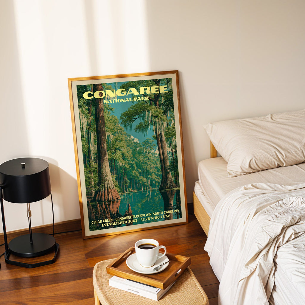 Cedar Creek Congaree poster in a gold frame on the floor beside a made bed and a black table lamp