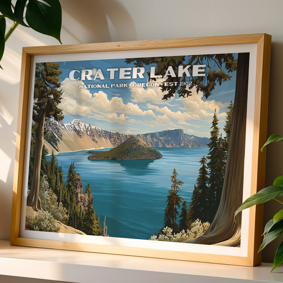 Crater Lake National Park wall art print in a light oak frame, leaning on a white shelf in warm sunlight beside a monstera plant