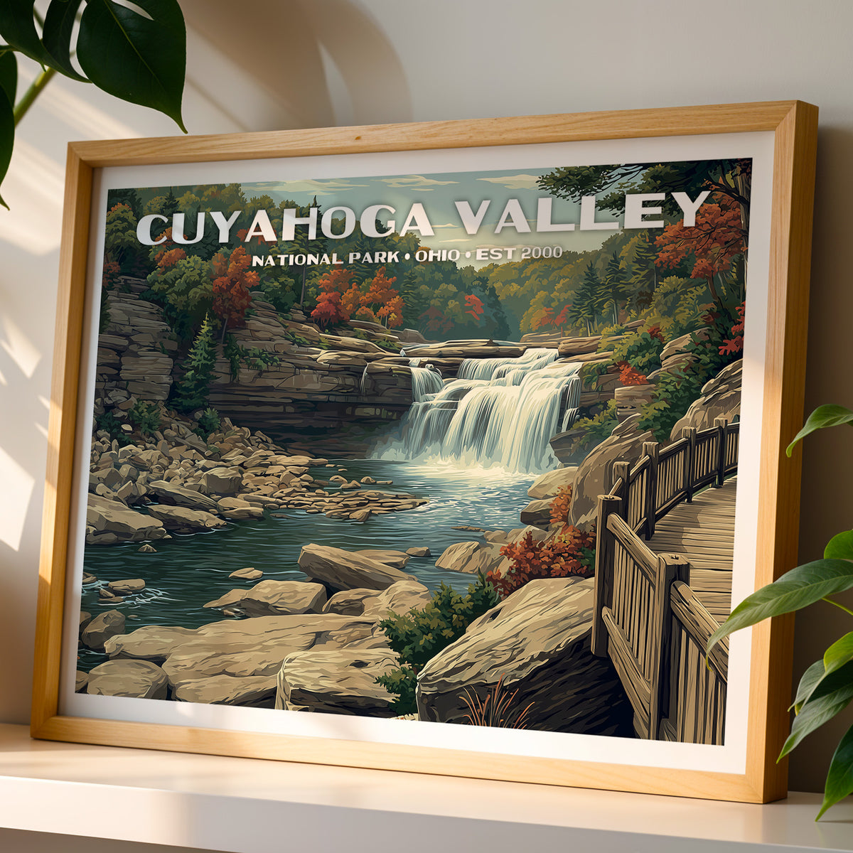 Cuyahoga Valley National Park wall art print in a light oak frame, leaning on a white shelf in warm sunlight beside a monstera plant