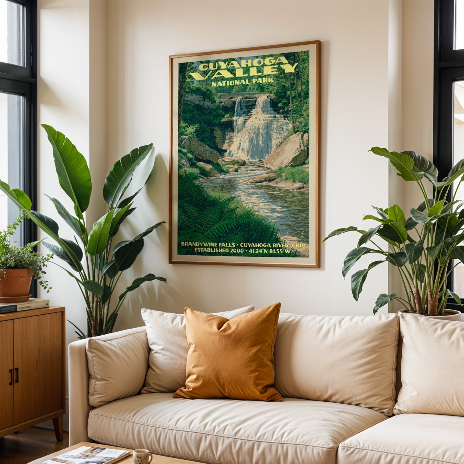 Cuyahoga Valley vintage travel print in oak above a cream sofa with a rust cushion and tall houseplants