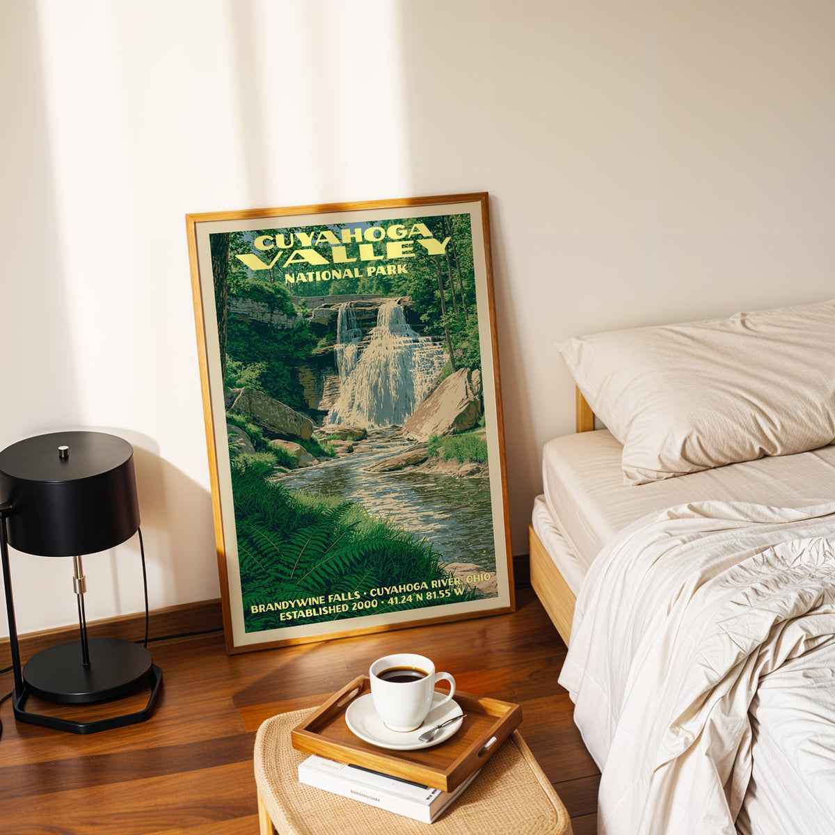 Brandywine Falls Cuyahoga Valley poster in a gold frame on the floor beside a made bed and a black lamp