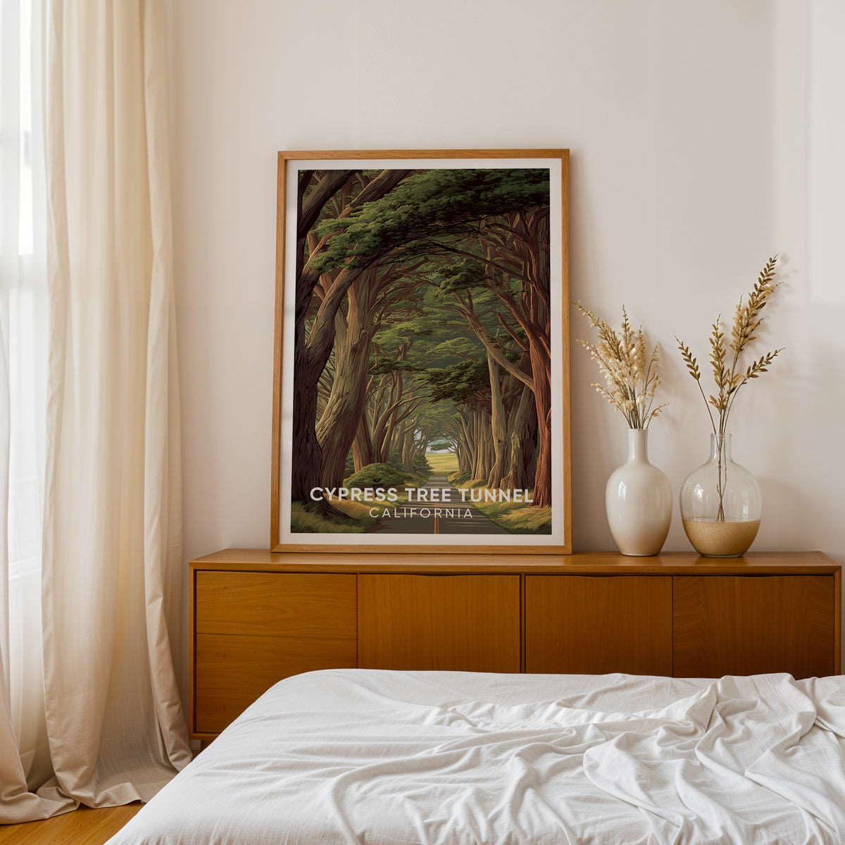 Point Reyes cypress print on a teak sideboard beside a bed with dried pampas in two white vases.