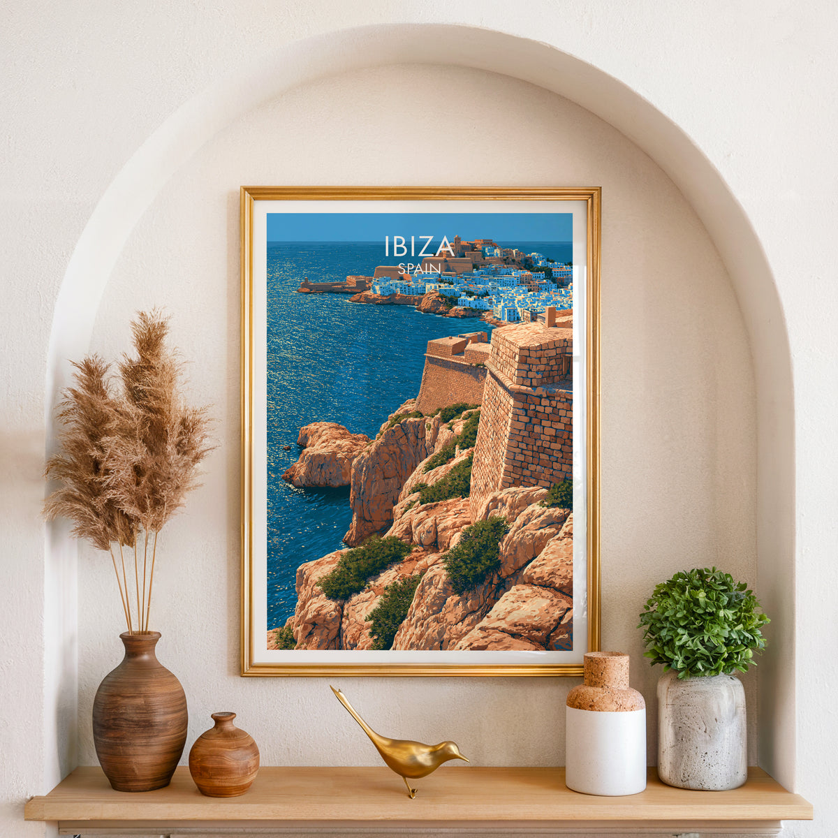 Ibiza walled town poster, gold frame in an arched wall niche above pampas grass in a clay vase