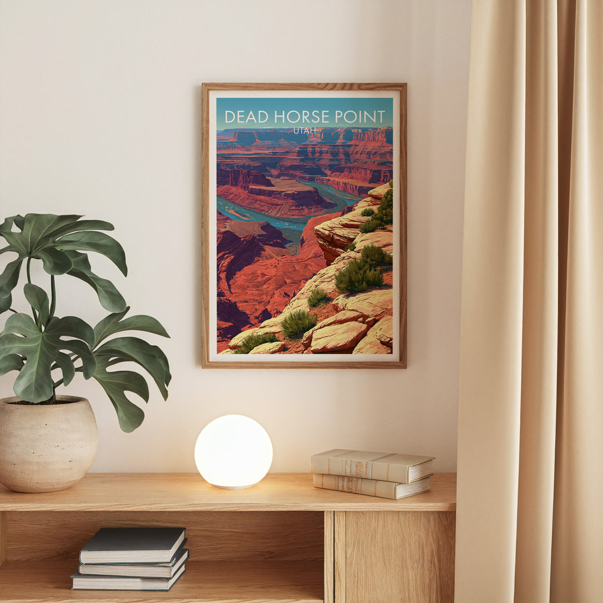 Utah desert poster in an oak frame on a beige wall over a console with a monstera and a globe lamp.