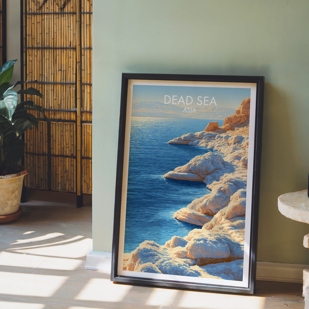Dead Sea Middle East wall art in a black frame leaning against a sage green wall beside a bamboo screen
