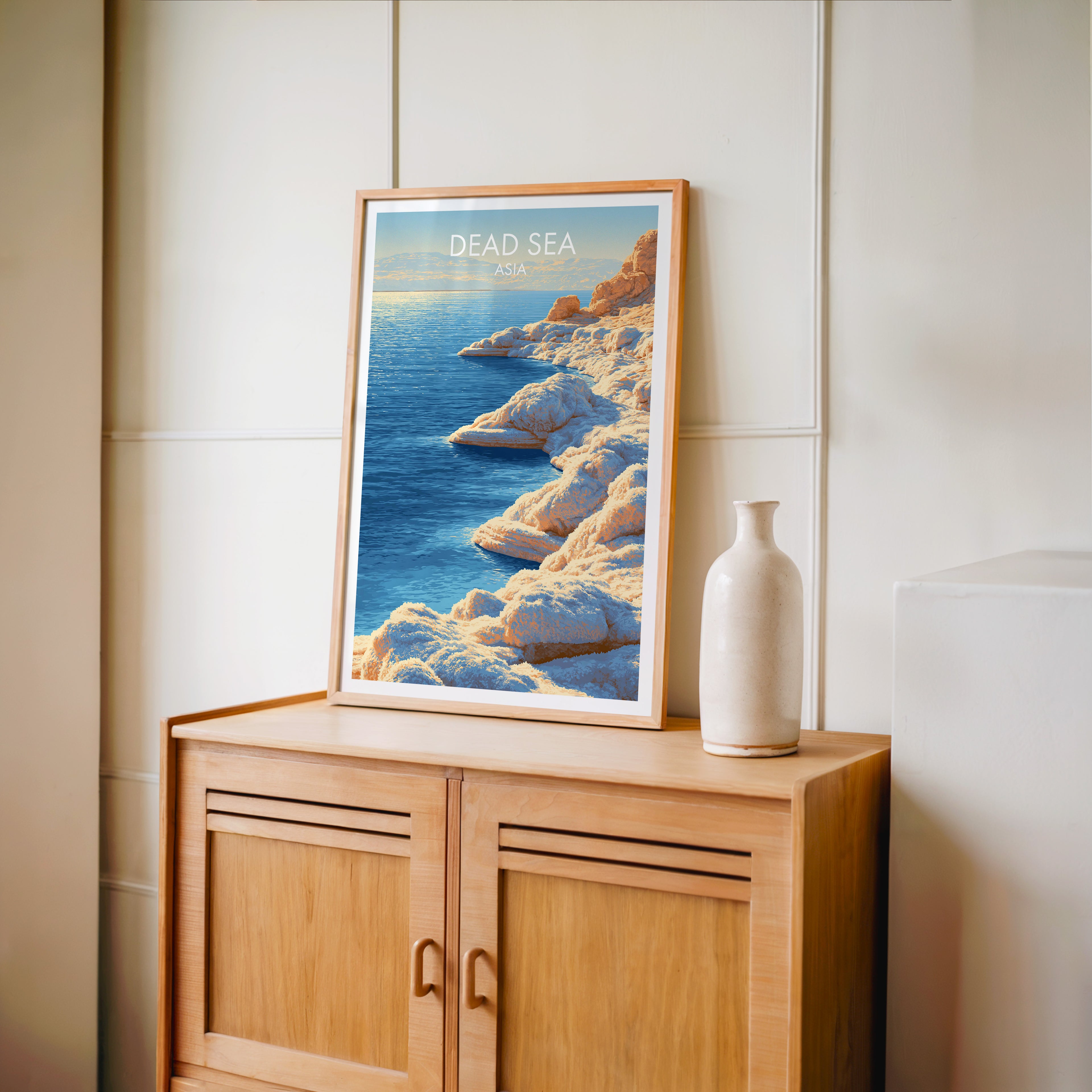 Small Dead Sea Middle East travel poster in an oak frame on a mid-century sideboard with a ceramic vase