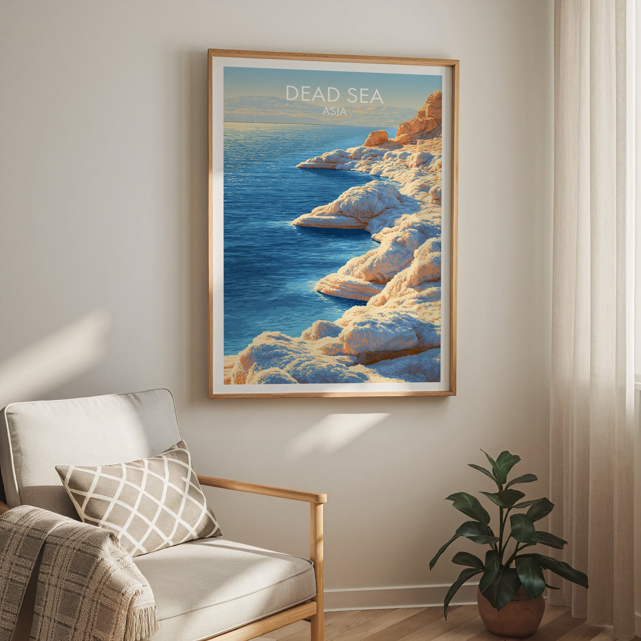 Dead Sea Middle East travel print in a light oak frame on a living room wall beside a linen armchair