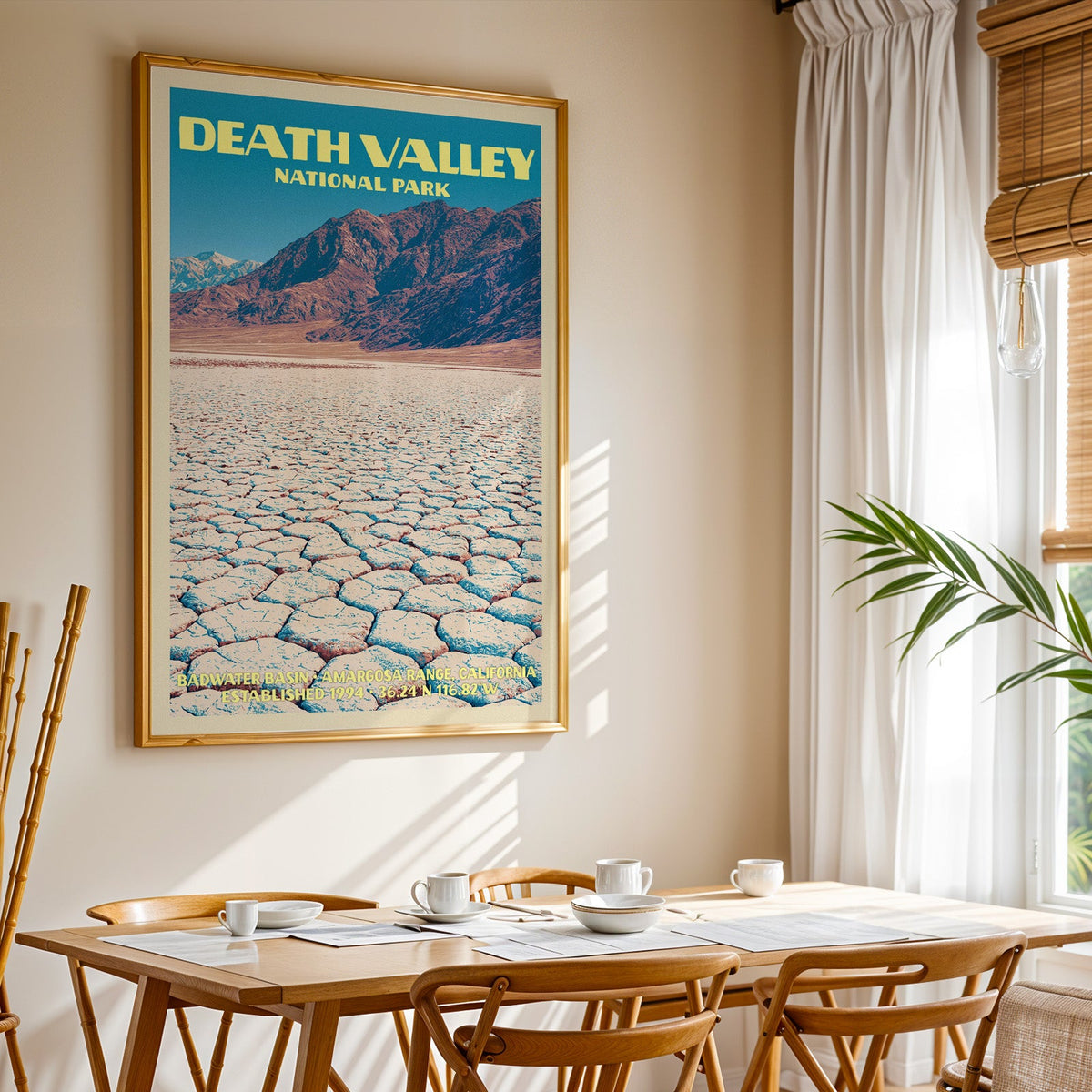 Death Valley National Park print in gold above a light oak dining table by a curtained window