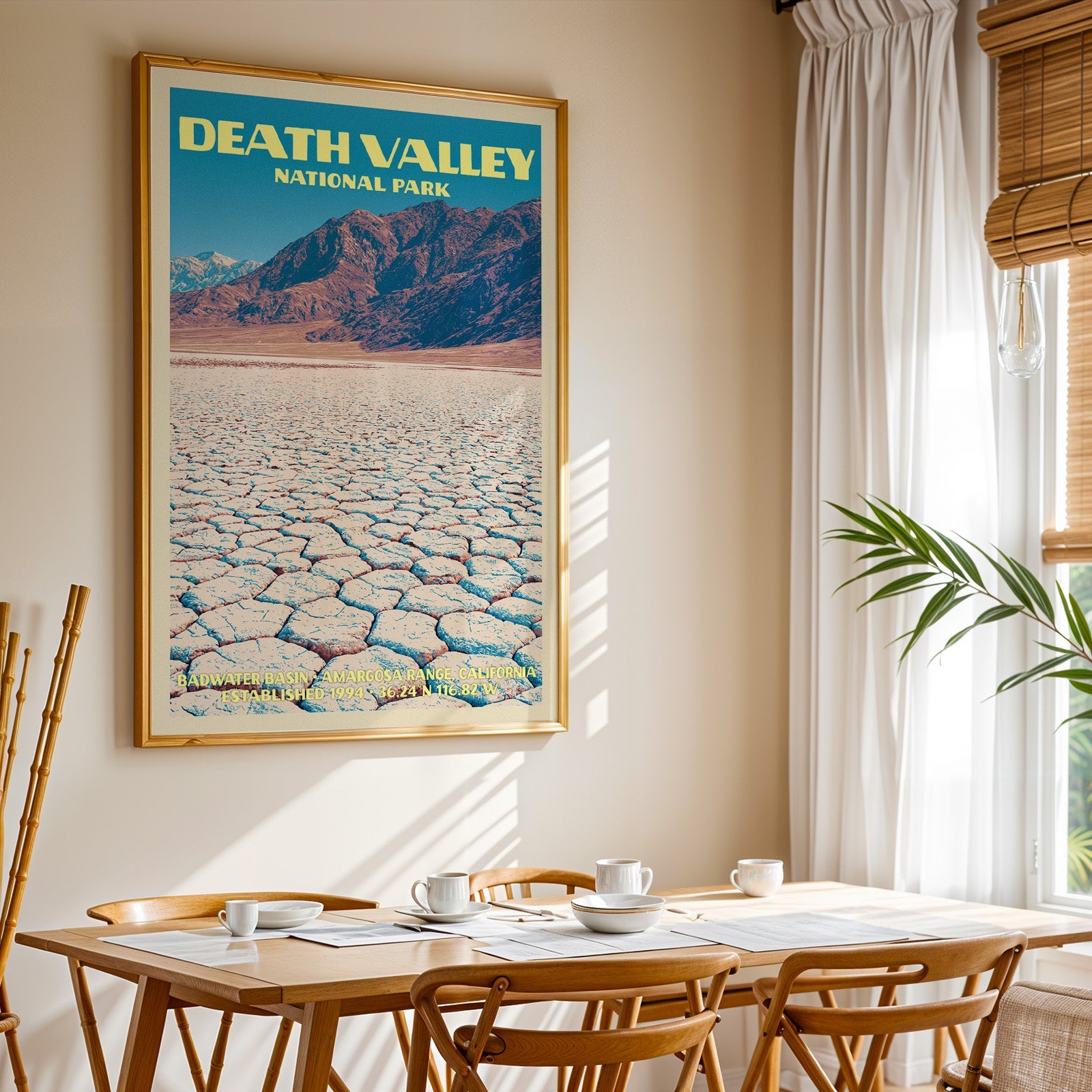 Death Valley National Park print in gold above a light oak dining table by a curtained window