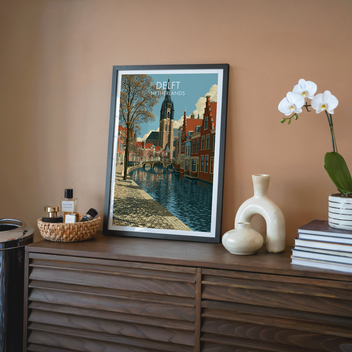 Delft Netherlands wall art, black frame on a walnut sideboard against a terracotta wall with a white orchid