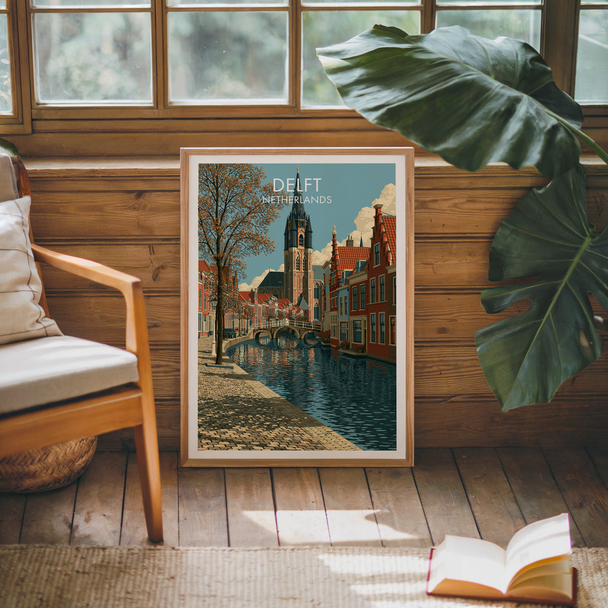 Delft travel poster, oak frame leaning on a wood-panelled sunroom wall by a mid-century armchair