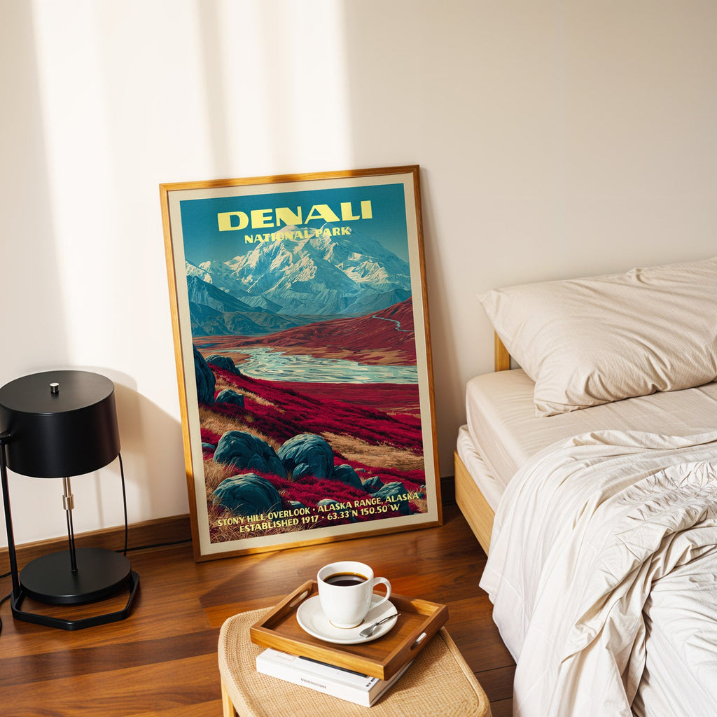 Stony Hill Overlook Denali poster in a gold frame on the floor beside a made bed and a black table lamp