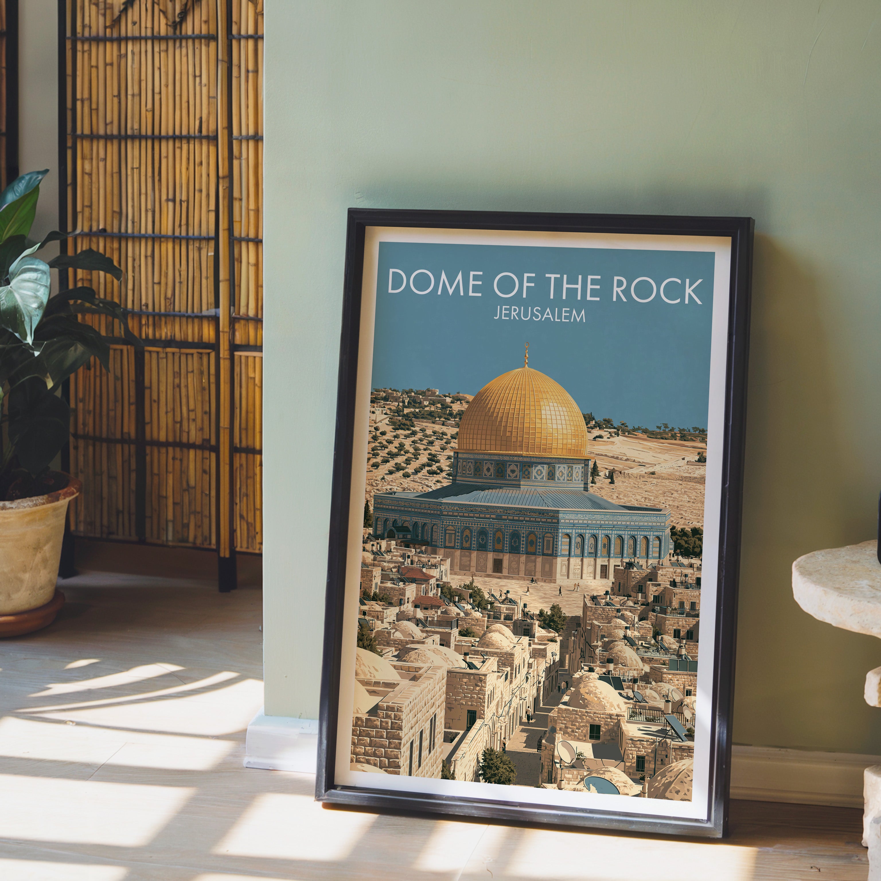 Dome of the Rock Jerusalem wall art in a black frame leaning against a sage green wall beside a bamboo screen