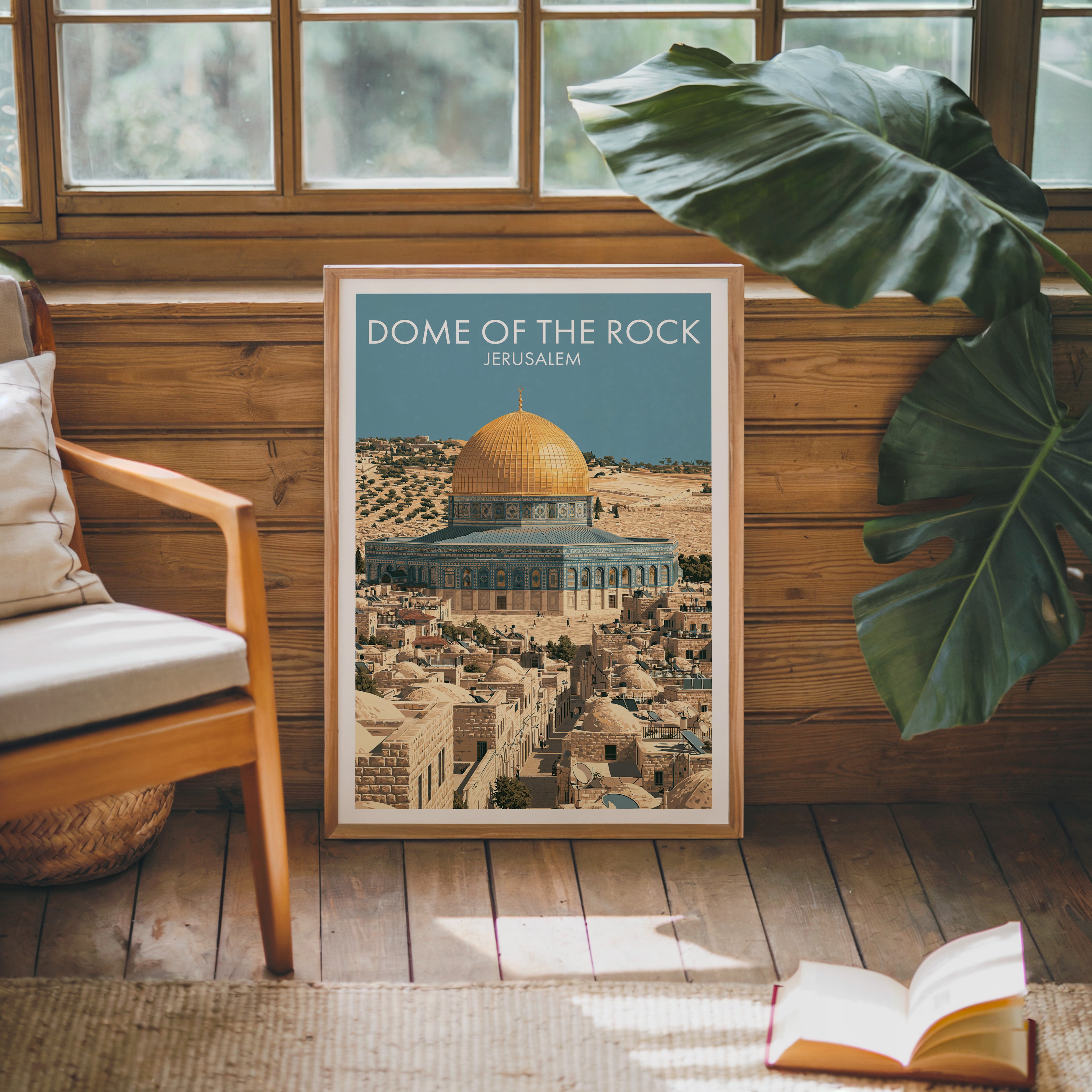 Framed Dome of the Rock Jerusalem poster leaning against a timber cabin wall with monstera leaves and an open book