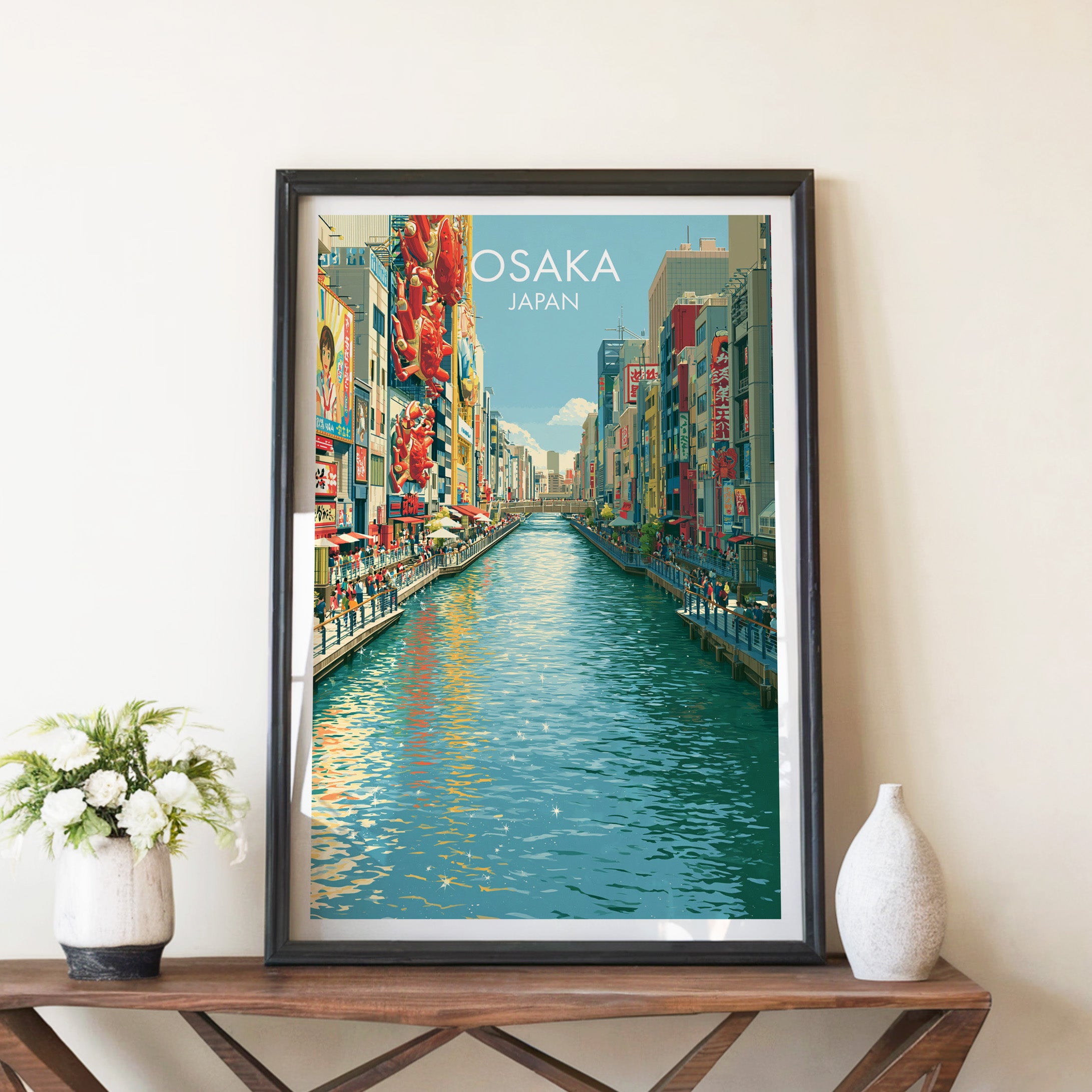 Dotonbori Osaka Japan travel poster in a black frame on a wooden console table with white flowers