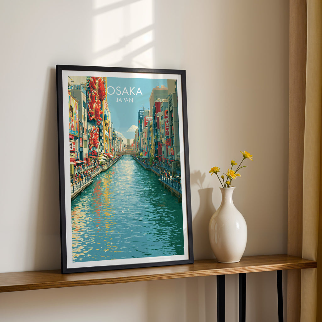 Black framed Dotonbori Osaka Japan print on a narrow hallway console in sunlight, styled with yellow flowers