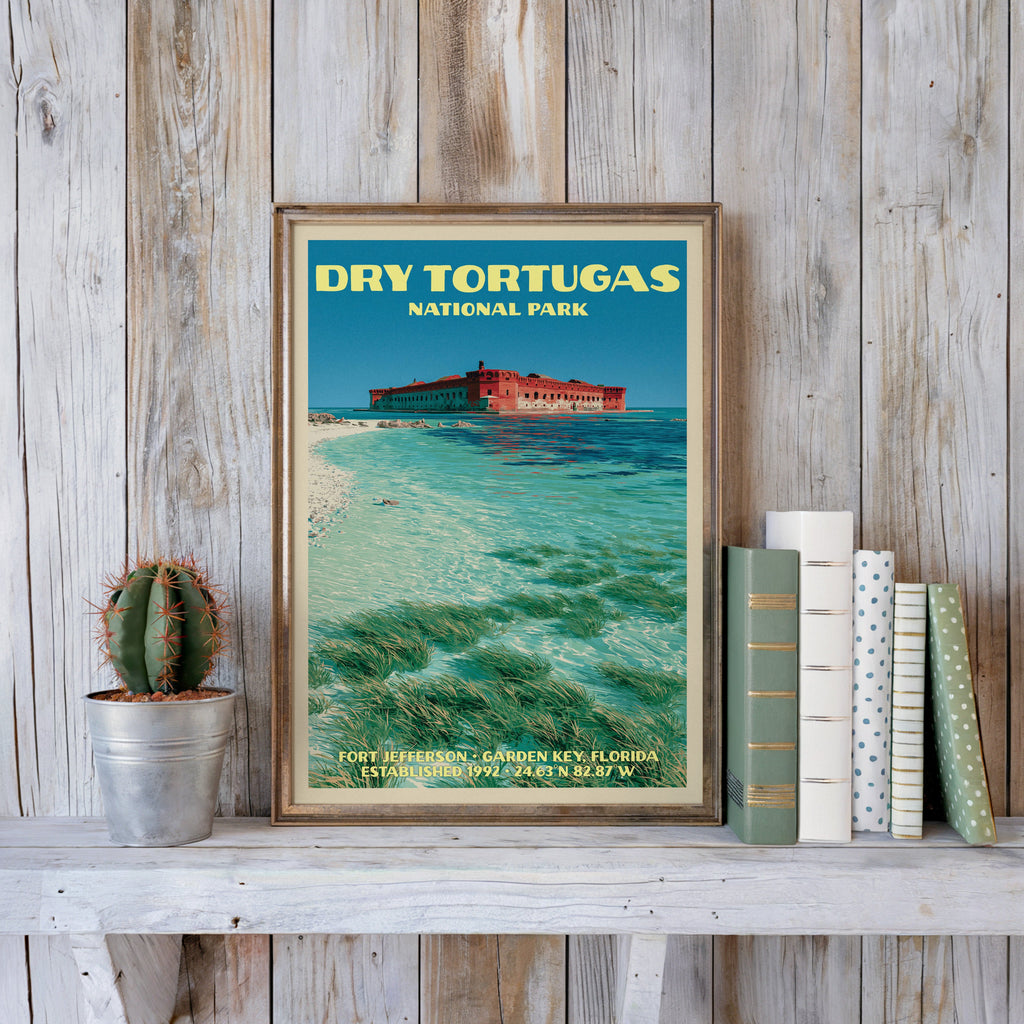 Dry Tortugas vintage poster in a slim gold frame on a whitewashed plank wall beside a cactus and pastel books