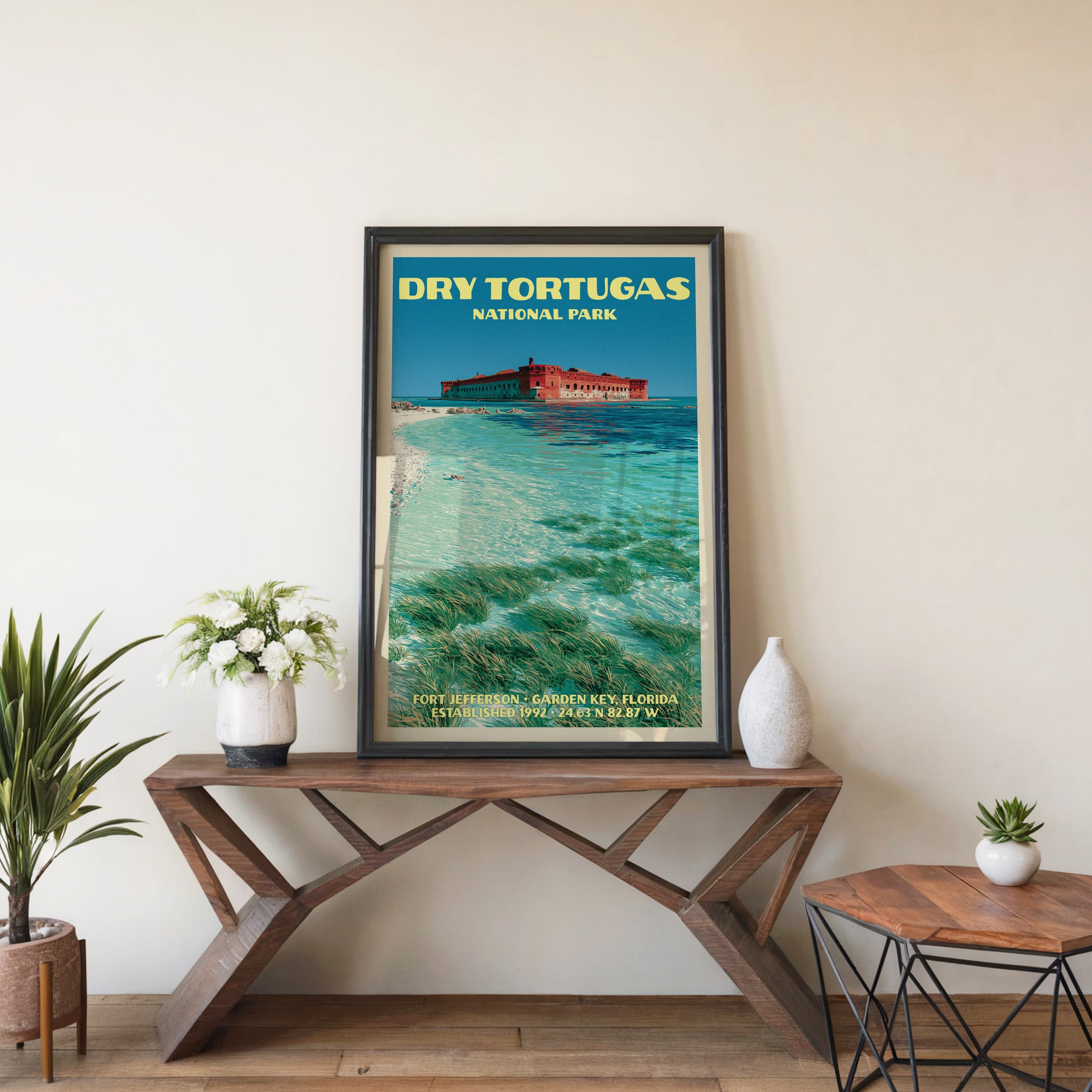 Dry Tortugas Fort Jefferson wall art in black, leaning on a walnut console with white anemones and a vase