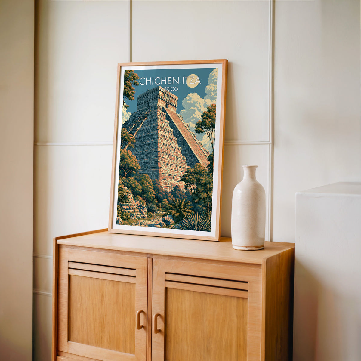 Mexico travel print in an oak frame on a light oak cabinet, cream panelled wall and a pale bottle vase