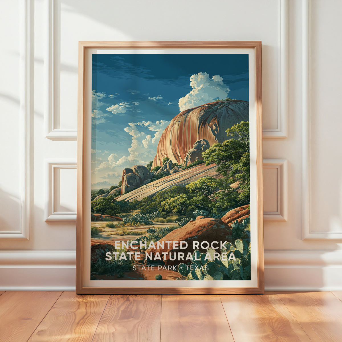 Enchanted Rock print in an oak frame propped on a textured white wall, sunlight falling across the floorboards.