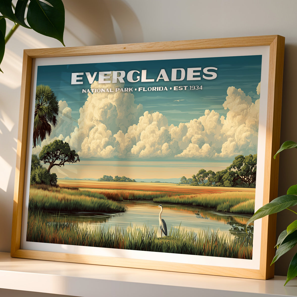 Everglades National Park wall art print in a light oak frame, leaning on a white shelf in warm sunlight beside a monstera plant